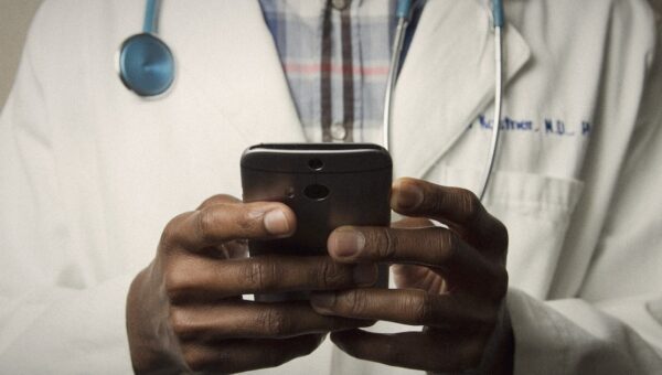 A doctor in a white coat holding a smartphone, hands close up