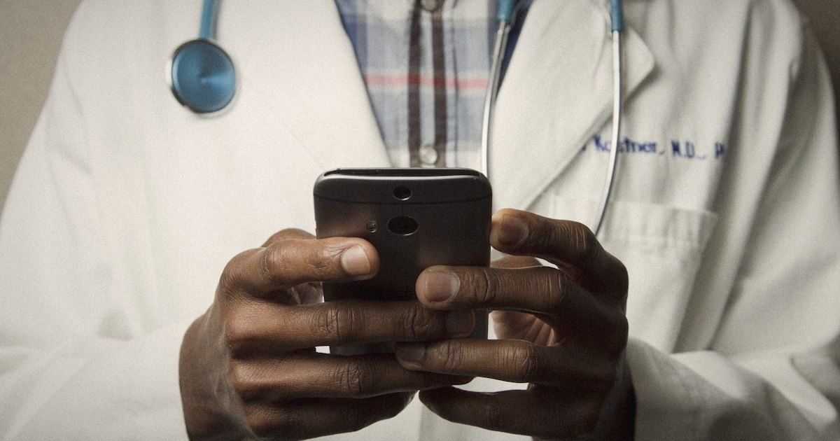 A doctor in a white coat holding a smartphone, hands close up